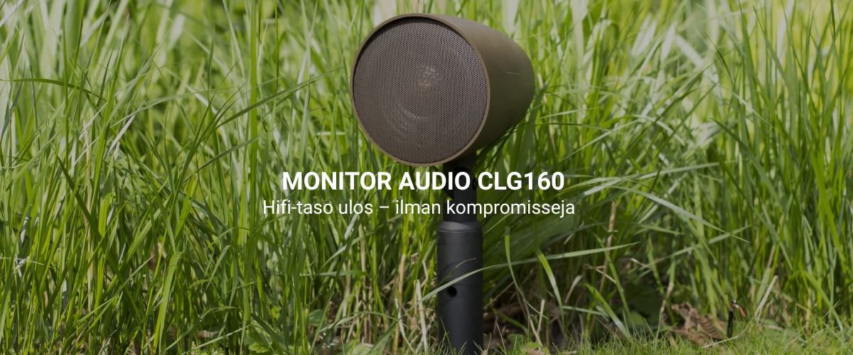 Monitor Audio CLG160 ruskea ulkokaiutin asennettuna puutarhaan kukkivien kasvien keskelle, maapiikillä näkymättömästi kiinnitettynä